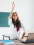 Female student raises hand sitting at the desk.