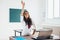 Female student raises hand sitting at the desk like a pupil.