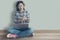 Female student relaxed sitting on a wooden floor at home and watching training online course and listening it with headphones