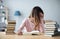 Female student sits at a table with books preparing for exams