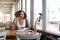 Female student sitting at cafe looking out of window daydreaming