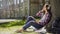 Female student sitting on grass, leaning against tree, listening to music, relax