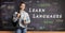 Female student standing in front of a blackboard with hello written in different languages