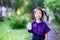 Female student standing holding white milk carton box. Sweet smiley girl wearing a purple school uniform.