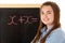 Female Student Standing Next To Blackboard