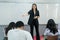 Female student stands in front of a classroom of her peers delivering a lecture