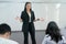 Female student stands in front of a classroom of her peers delivering a lecture