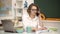 Female student studying in university. Young teacher in glasses over green chalkboard.