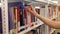 Female student taking book from shelf in library