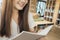 Female student taking notes from a book at library. Young asian woman sitting at table doing assignments in college library.