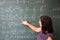 Female student or teacher in the classroom writing on chalkboard mathematical equations