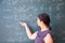 Female student or teacher in the classroom writing on chalkboard mathematical equations