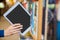 Female student tidying a tablet in a bookshelf