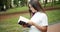 Female Student Walking and Reading Book in Park