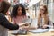 Female Students Working In Communal Area Of Busy College Campus