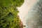 Female sunbathing on tropical sandy beach surrounded by palm trees and turquoise blue ocean lagoon. Aerial drone shot