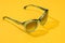 Female sunglass in sunlight on summer pastel yellow background. Women stylish eyeglasses for banner. Transparent plastic