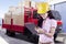 Female supervisor with safety helmet looking through checklist in front of truck carrying boxes