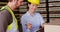 Female supervisors laughing while writing on clipboard in warehouse