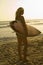 Female surfer carrying surfboard on beach