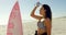 Female surfer drinking water on the beach 4K 4k