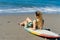 female surfer in swimsuit resting on surfboard on beach