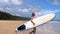 Female surfer walking with board on empty sandy beach. Young woman with surfboard on summer vacation, water sports