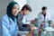 Female surgeon in hijab looking at camera while using laptop at table in hospital