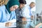 Female surgeon in hijab writing on clipboard at table in the hospital