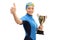 Female swimmer holding gold trophy and making thumb up gesture