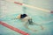 A female swimmer in indoor sport swimming pool trying to dive.