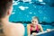 Female swimmer in an indoor swimming pool , talking to a friend