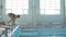Female swimmer jumps off starting block and start swims in pool HD slow-motion video. Professional athlete training