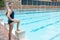 Female swimmer standing with hand on hips at poolside