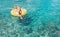 Female swims on inflatable pineapple pool ring in crystal clear sea lagoon