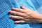 Female tanned hand with red nails lying on a blue fabric, people sunbathing