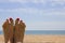 Female tanned legs with a bright pedicure on the sandy beach