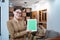 female teacher in a civil servant uniform wearing glasses smiling while showing a digital tablet