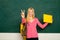 Female teacher in the classroom on the chalkboard. College girl in class. Student girl holding empty faper for product.