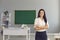 Female teacher with crossed arms posing in empty classroom. Professor at school, ready to start lesson