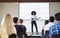 Female Teacher With Digital Tablet Giving Presentation To High School Class In Front Of Screen