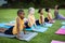 Female teacher and group of diverse students performing stretching exercise in the garden at school