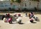 Female teacher in head scarf at school collecting the girls in circle and drawing on the sand