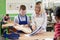 Female Teacher Helping Male High School Student Building Guitar