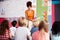 Female Teacher Reading Story To Group Of Elementary Pupils In School Classroom