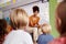 Female Teacher Reading Story To Group Of Elementary Pupils In School Classroom