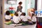 Female Teacher Reading Story To Group Of Elementary Pupils Wearing Uniform In School Classroom