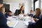 Female teacher sitting at a table with a group of schoolchildren in a primary school lesson, low angle, selective focus