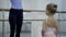 Female teacher teaches little girl in ballet school.