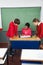 Female Teacher Teaching Teenage Students At Desk